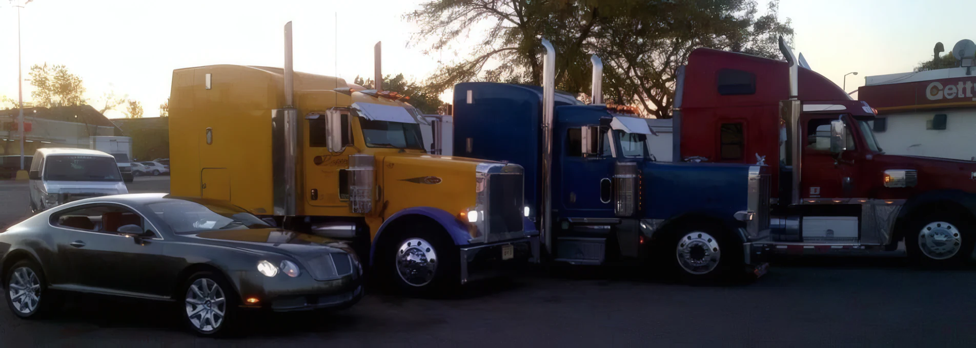 Line of sleeper-cab tractors parked side by side at dusk