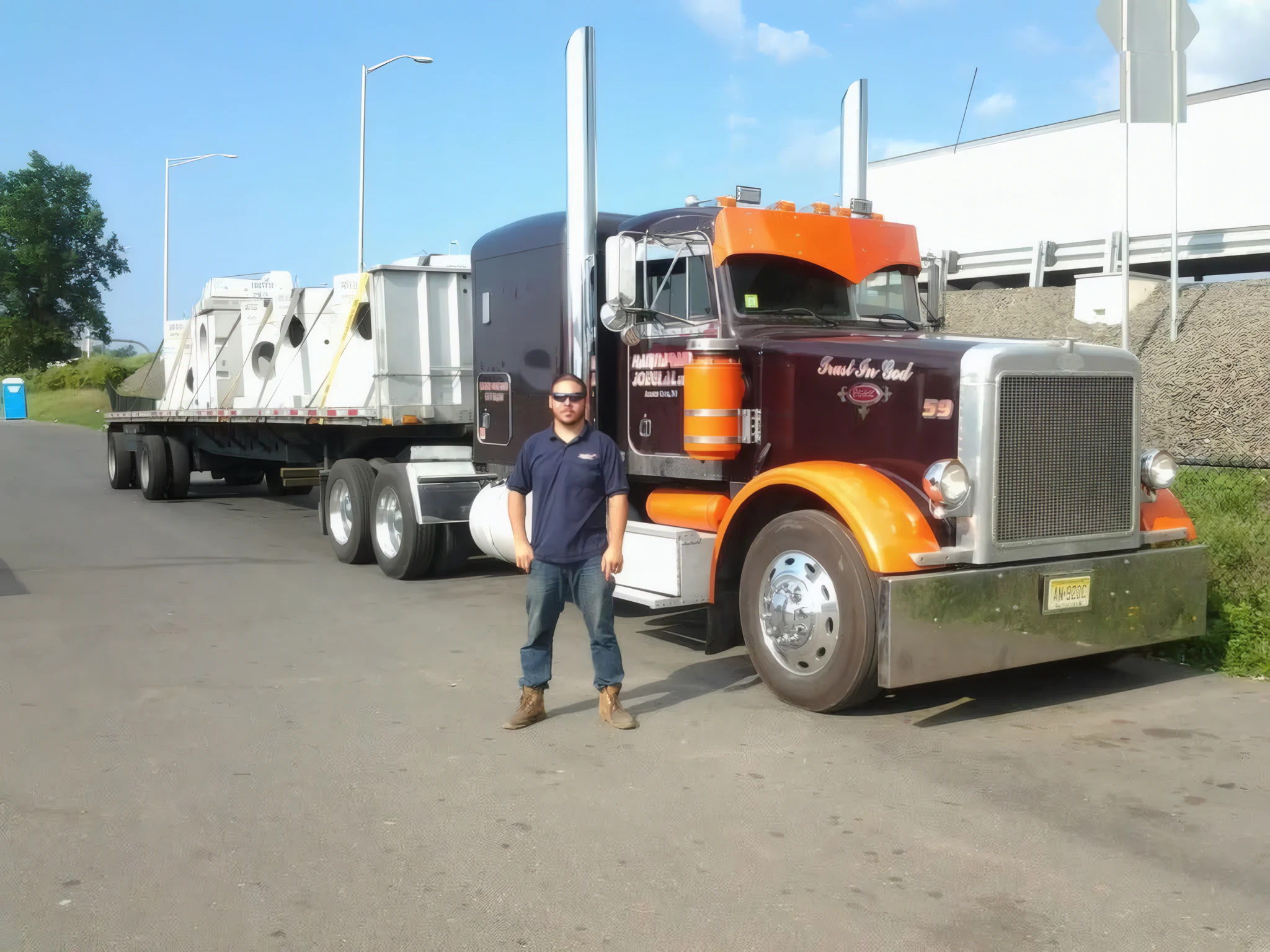 MC Global flatbed load secured on a classic Peterbilt at a New Jersey yard, driver standing by the rig
